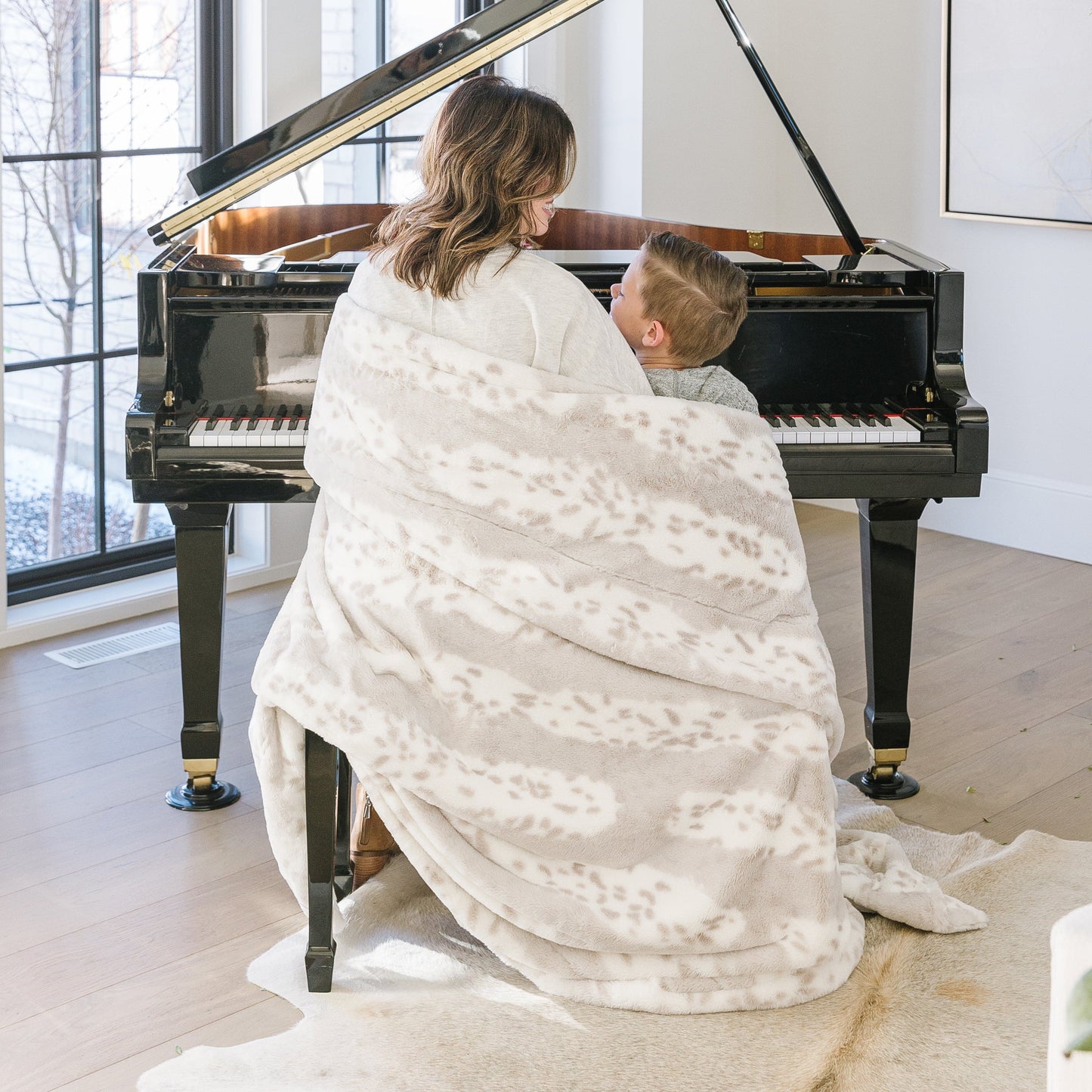 Woman wrapped in Arctic Lynx Posh Minky Blanket, playing a piano