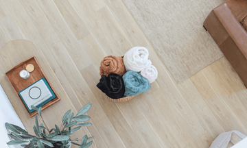 Assorted Chic minky blankets from Minky Designs displayed in a woven basket on a hardwood floor in a cozy living room.